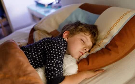 Ein Kind liegt im Bett und schläft.