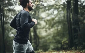 Mann mit Depressionen geht im Wald joggen, da Sport bei Depressionen helfen kann.