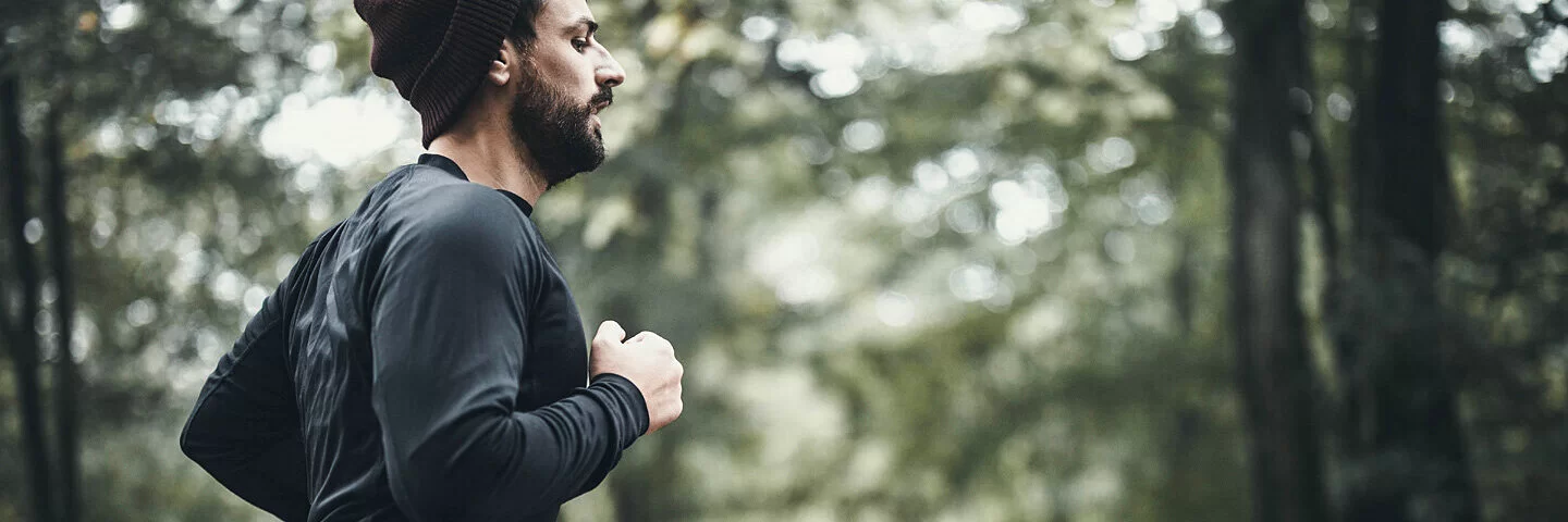 Mann mit Depressionen geht im Wald joggen, da Sport bei Depressionen helfen kann.