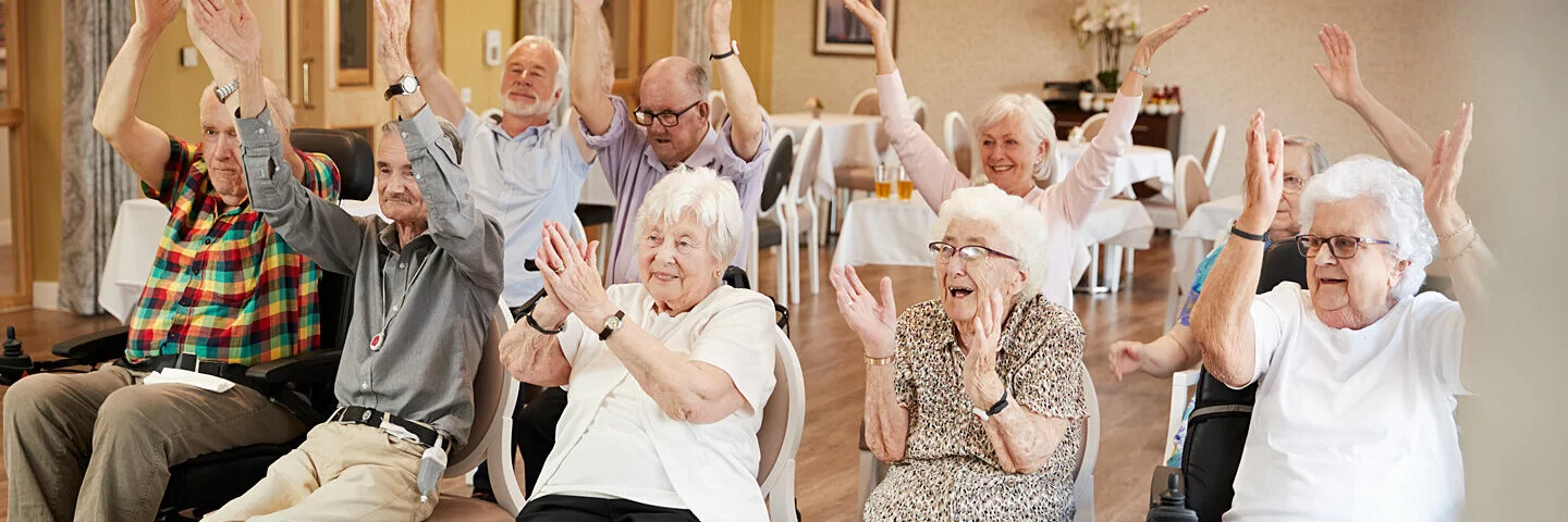 Eine Gruppe pflegebedürftiger älterer Menschen bei einem Bewegungskurs im Pflegeheim.
