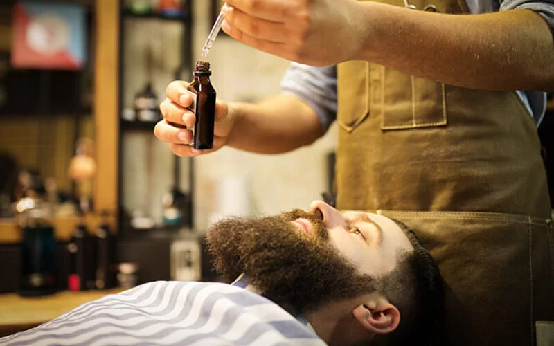 Ein Mann mit großem Bart ist beim Barbier für die Bartpflege.