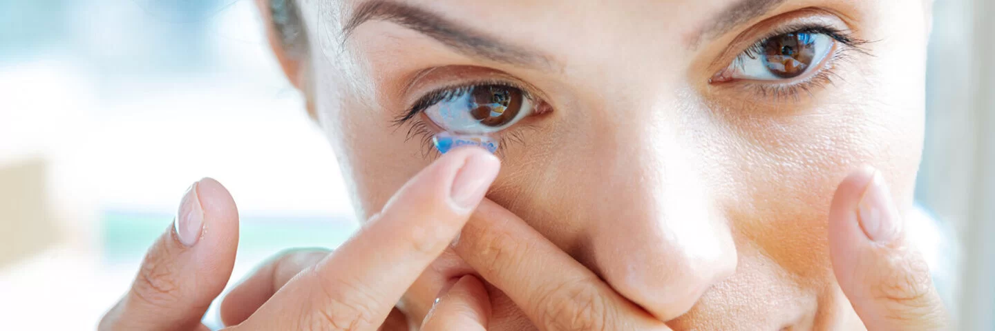 Eine Frau setzt mit dem Finger eine Kontaktlinse ein.