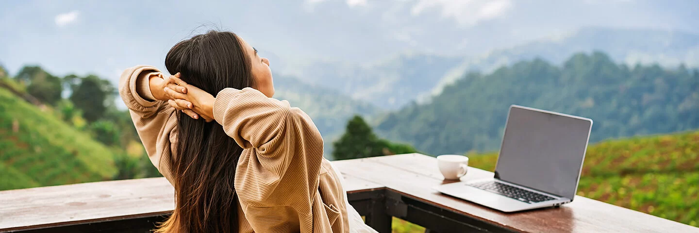 Frau macht Workation und genießt ihren Ausblick auf die Berge.