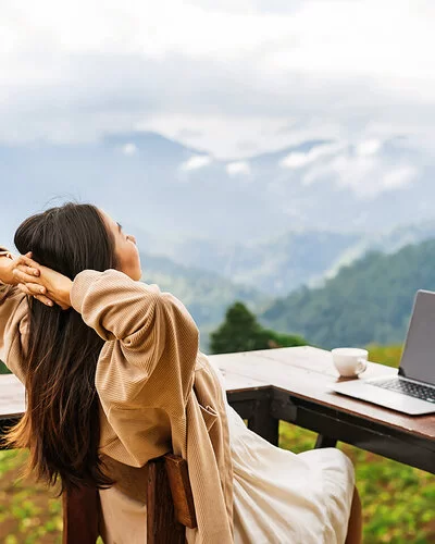 Frau macht Workation und genießt ihren Ausblick auf die Berge.