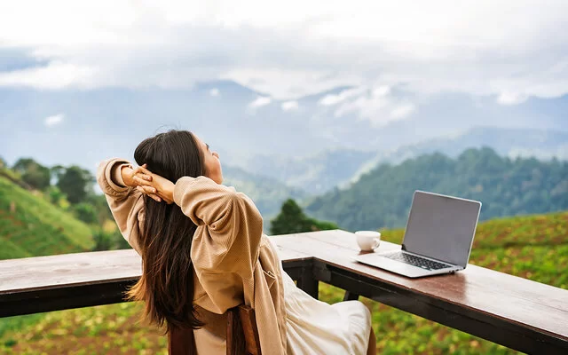 Frau macht Workation und genießt ihren Ausblick auf die Berge.