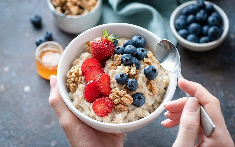 Schüssel mit eingeweichten Haferflocken, Nüssen und Beeren.