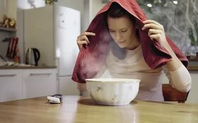 Frau inhaliert über einer dampfenden Schüssel