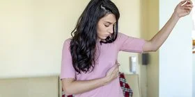 Brustkrebsfrüherkennung: Eine junge Frau tastet ihre Brust ab. 