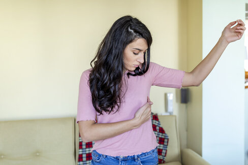 Brustkrebsfrüherkennung: Eine junge Frau tastet ihre Brust ab. 