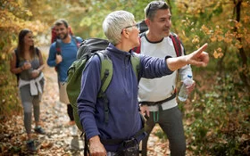 Eine Gruppe von fünf Menschen mit Rucksäcken wandert durch einen herbstlichen Wald.