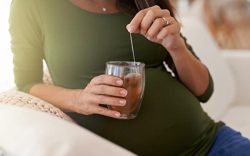 Eine schwangere Frau trinkt einen Tee.