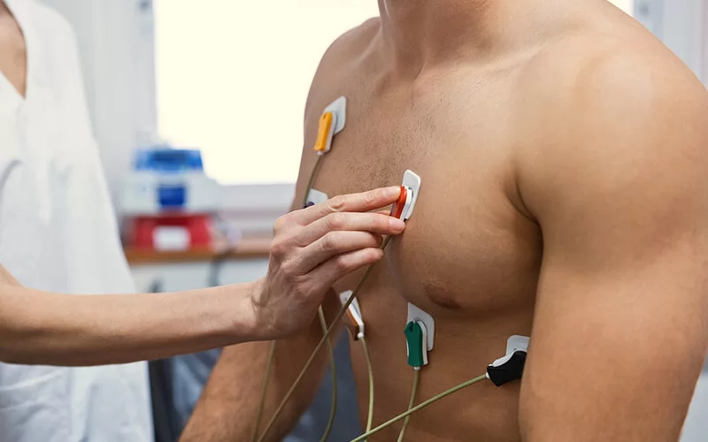 Kardiologin legt einem Patienten Elektroden für ein EKG an.