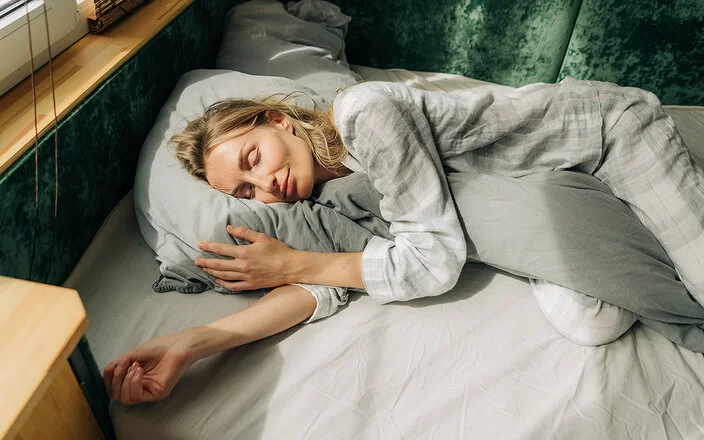 Warum träumen wir? Eine Frau liegt in ihrem Bett und schläft.