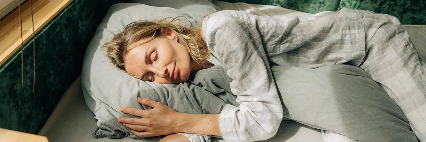 Warum träumen wir? Eine Frau liegt in ihrem Bett und schläft.