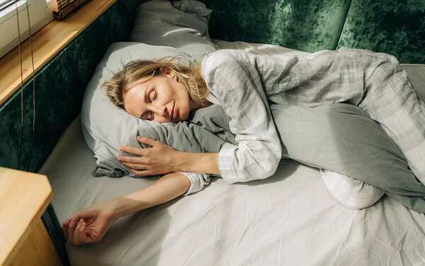Warum träumen wir? Eine Frau liegt in ihrem Bett und schläft.