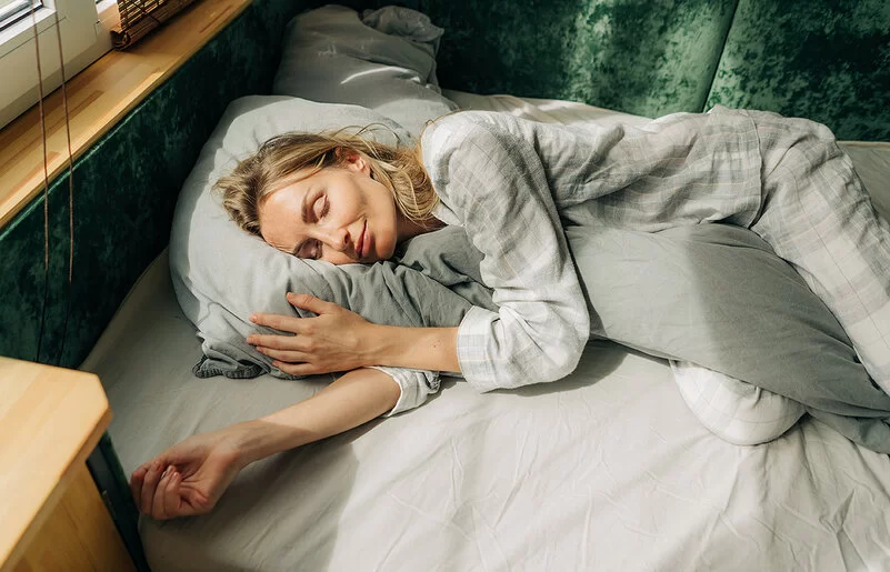 Warum träumen wir? Eine Frau liegt in ihrem Bett und schläft.