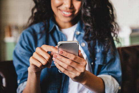 Eine junge Frau betrachtet ihr Smartphone. Die AOK bietet ihr die Möglichkeit einer elektronischen Patientenakte.