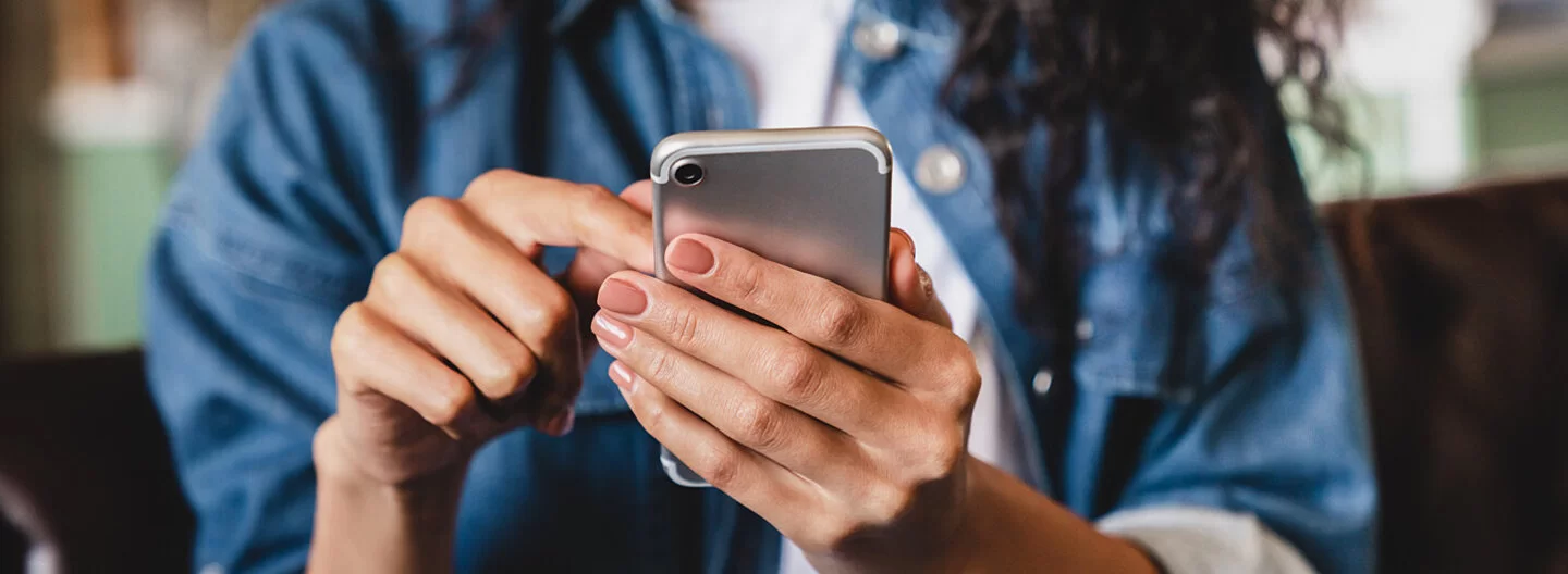 Eine junge Frau betrachtet ihr Smartphone. Die AOK bietet ihr die Möglichkeit einer elektronischen Patientenakte.