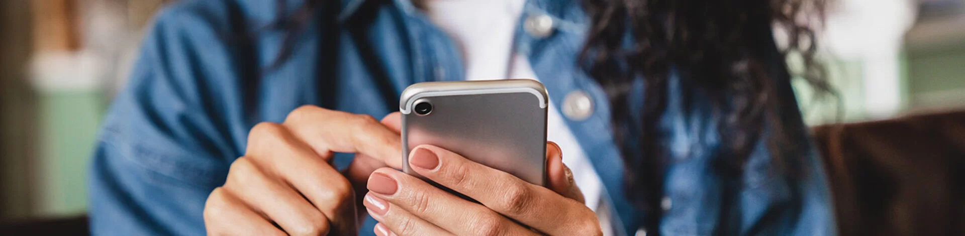 Eine junge Frau betrachtet ihr Smartphone. Die AOK bietet ihr die Möglichkeit einer elektronischen Patientenakte.