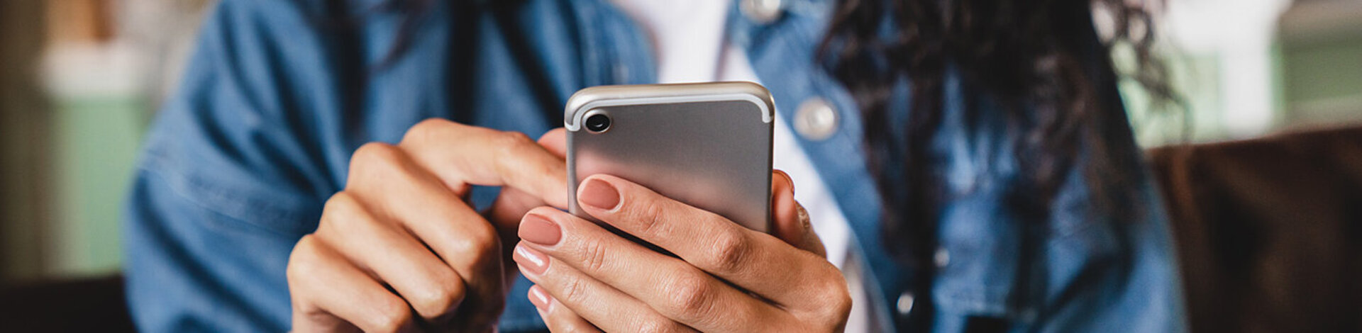 Eine junge Frau betrachtet ihr Smartphone. Die AOK bietet ihr die Möglichkeit einer elektronischen Patientenakte.