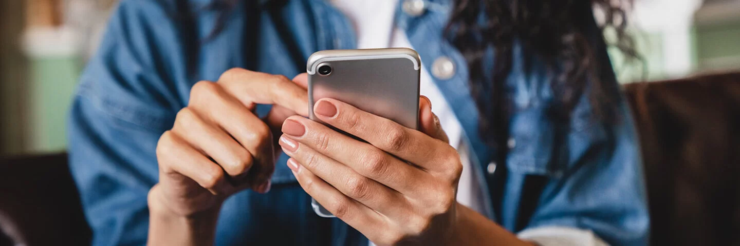 Eine junge Frau betrachtet ihr Smartphone. Die AOK bietet ihr die Möglichkeit einer elektronischen Patientenakte.