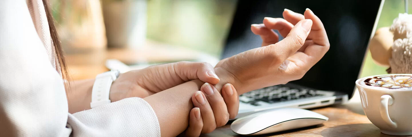 Frau mit Karpaltunnelsyndrom greift sich an ihr schmerzendes Handgelenk.