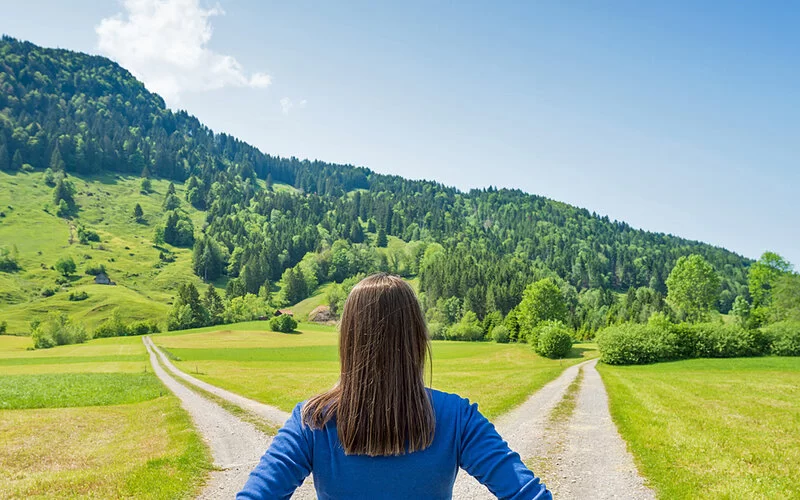 Eine Frau steht vor einer Wegkreuzung.