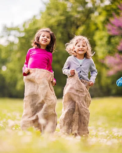 Auf einem Kindergeburtstag spielen Kinder Sackhüpfen.