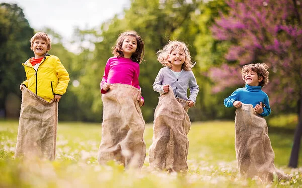 Auf einem Kindergeburtstag spielen Kinder Sackhüpfen.