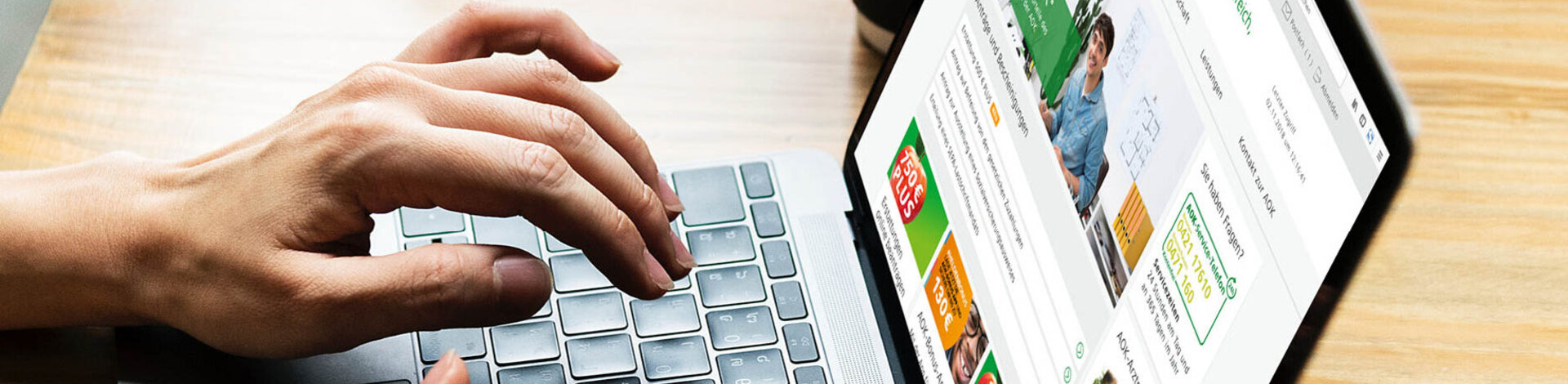 Das Foto zeigt tippende Hände auf einer Laptop-Tastatur. Auf dem Bildschirm sieht man die Website der AOK.