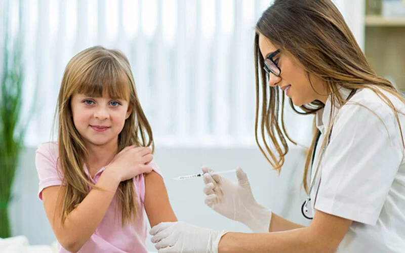 Eine Ärztin verabreicht einem jungen Mädchen die HPV-Impfung.