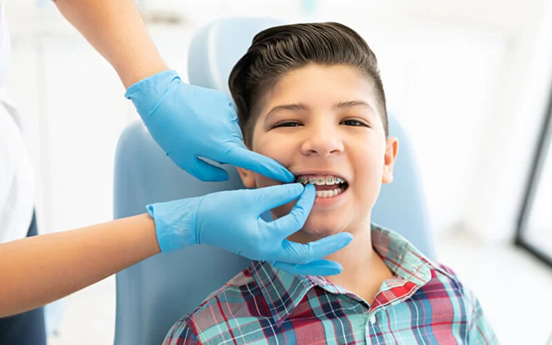 Ein Junge ist beim Zahnarzt, seine Zahnspange wird kontrolliert.