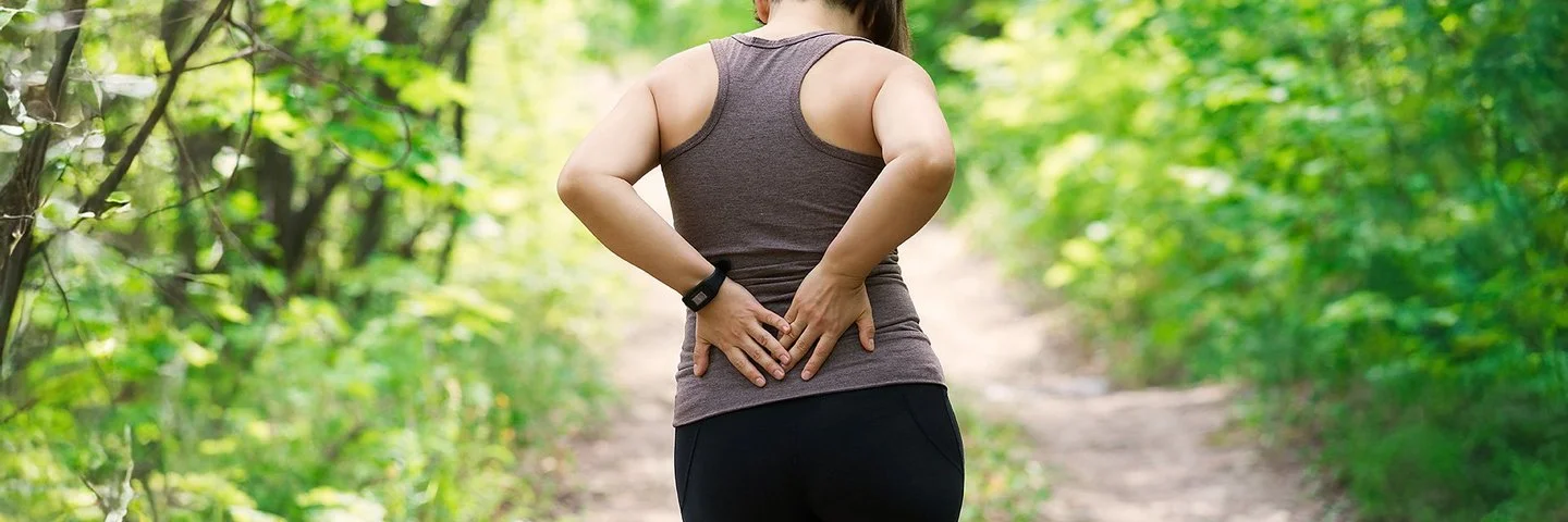 Eine Frau hält sich mit den Händen ihren unteren Rücken.