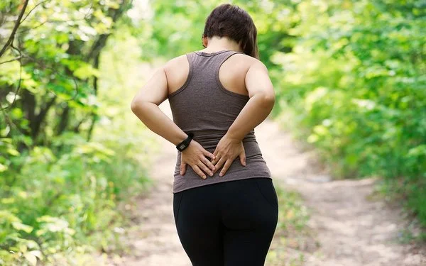 Eine Frau hält sich mit den Händen ihren unteren Rücken.
