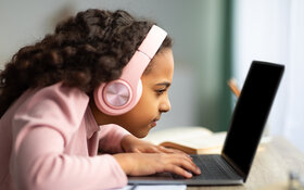 Ein Mädchen mit Kurzsichtigkeit ist mit ihrem Gesicht nah an einem Laptop.