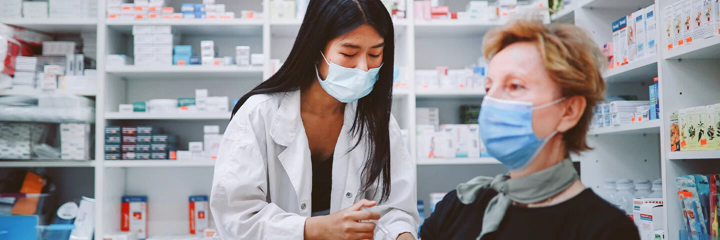 Eine Ärztin gibt einer Frau eine Grippeschutzimpfung. Beide tragen Masken.