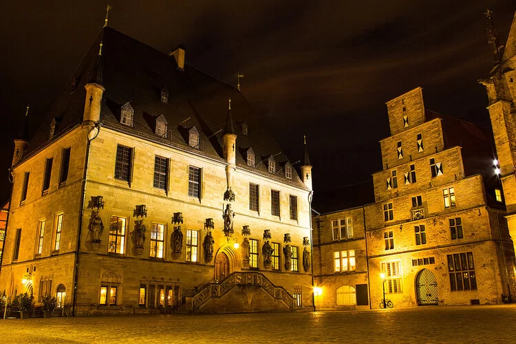 Beleuchtetes Rathaus in Osnabrück bei Nacht.