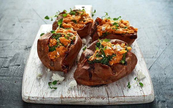 Gefüllte Süßkartoffeln vom Grill, garniert mit Feta und frischen Kräutern.