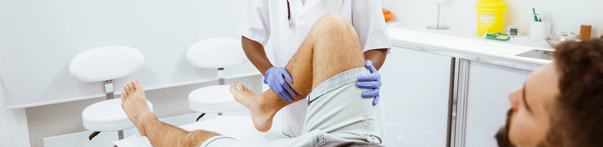 Ein Orthopädie untersucht das Knie eines Patienten.