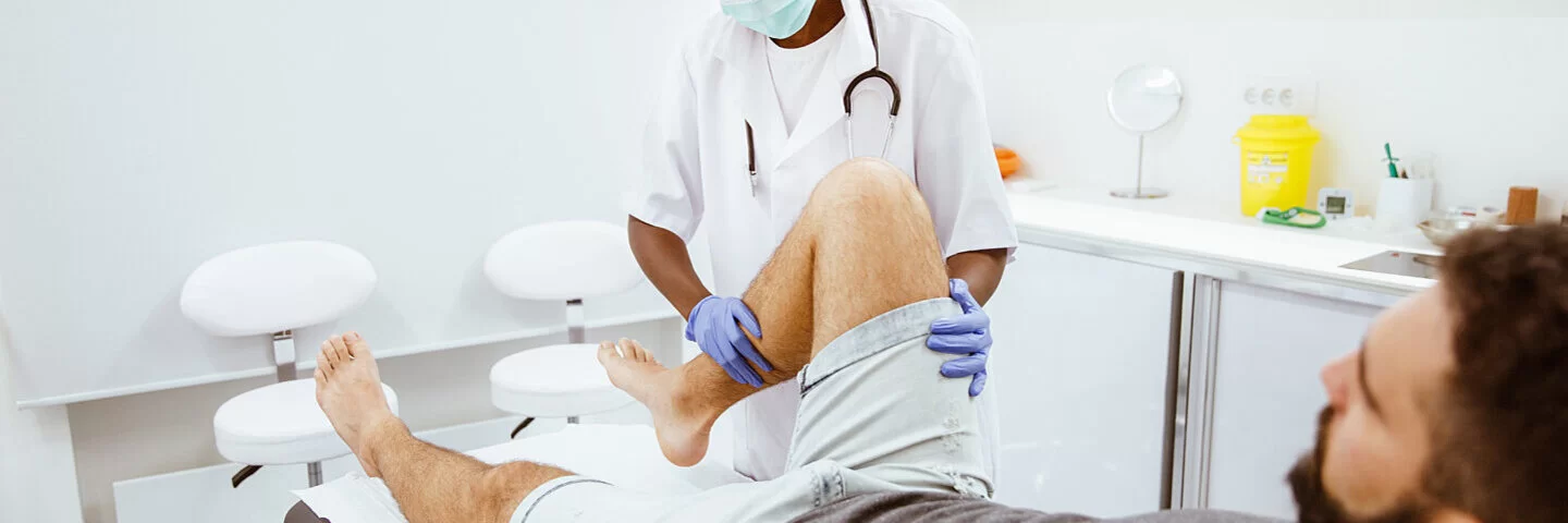 Ein Orthopädie untersucht das Knie eines Patienten.