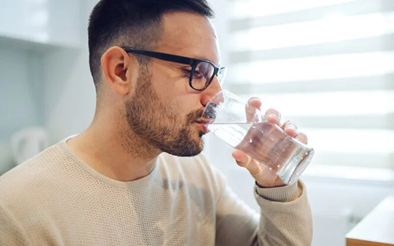 Ein Mann trinkt stilles Wasser aus einem Glas