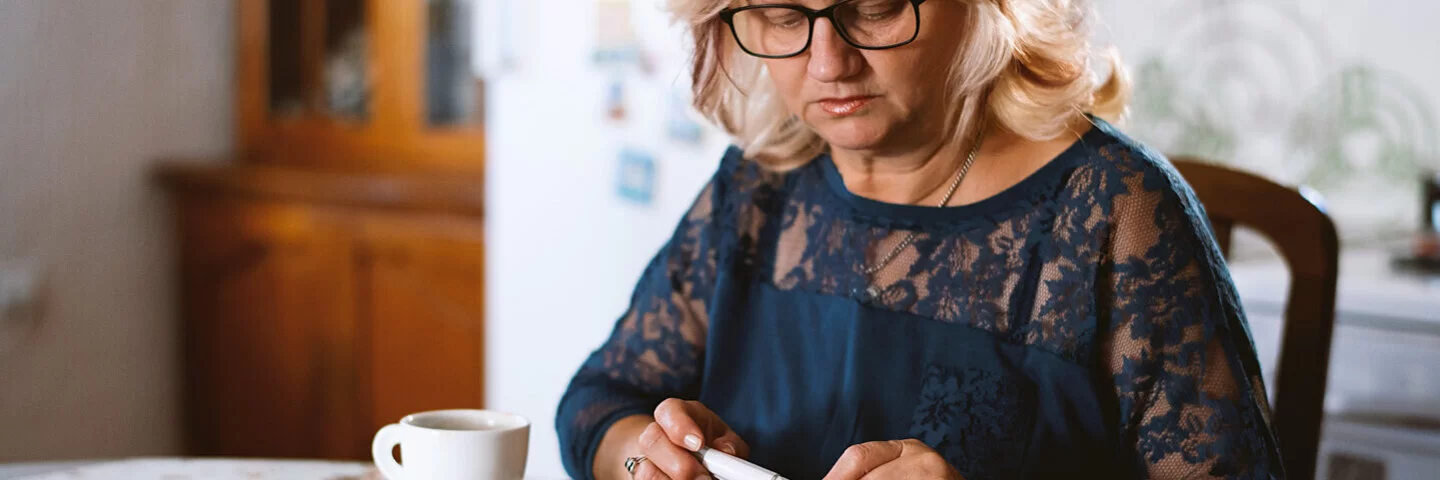 Eine Frau mit Diabetes misst ihren Blutzucker und plant ihr Frühstück.