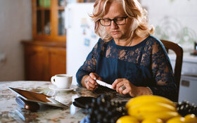 Eine Frau mit Diabetes misst ihren Blutzucker und plant ihr Frühstück.