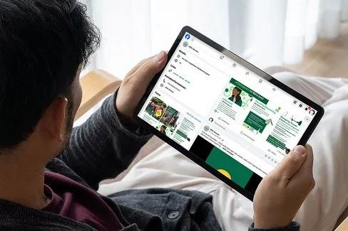 Ein Mann sitzt in seinem Sessel und blickt auf den Bildschirm seines Tablets.