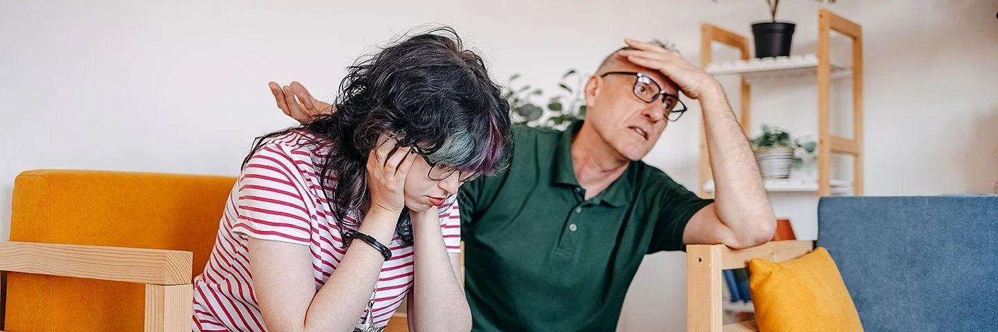 Ein Mädchen im Teenageralter und ihr Vater führen im Wohnzimmer ein ernsthaftes Gespräch.
