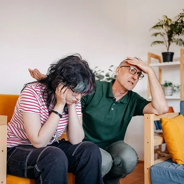 Ein Mädchen im Teenageralter und ihr Vater führen im Wohnzimmer ein ernsthaftes Gespräch.