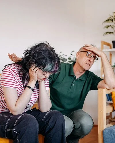 Ein Mädchen im Teenageralter und ihr Vater führen im Wohnzimmer ein ernsthaftes Gespräch.