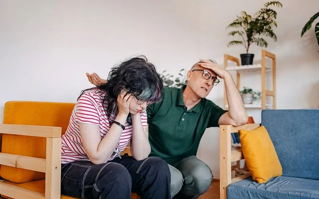 Ein Mädchen im Teenageralter und ihr Vater führen im Wohnzimmer ein ernsthaftes Gespräch.