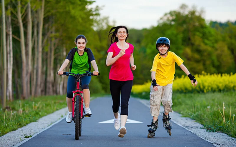 Mutter treibt draußen Sport mit ihren Kindern.