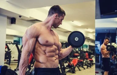 Ein junger Bodybuilder mit freiem, muskulösen Oberkörper macht einen Bizepscurl mit einer Kurzhantel.